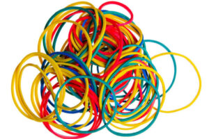 A collection of colourful rubber bands sits in a pile on a solid white background.